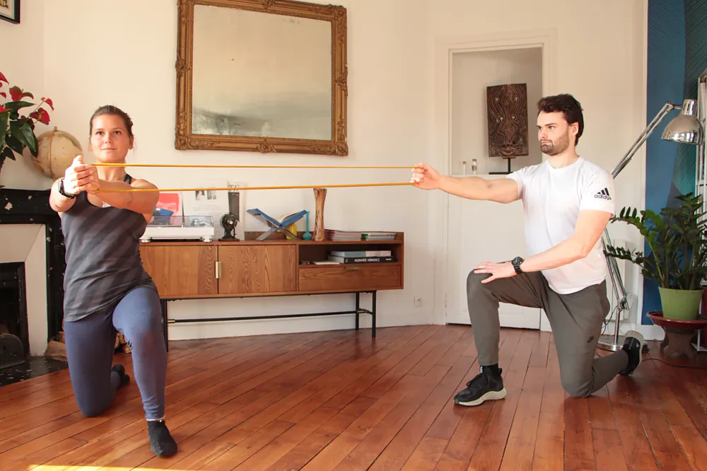 Alexis Glomeron, coach sportif, tient un &eacute;lastique en fente face &agrave; une cliente qui tire l'autre extr&eacute;mit&eacute;, dans un salon parisien au parquet ancien